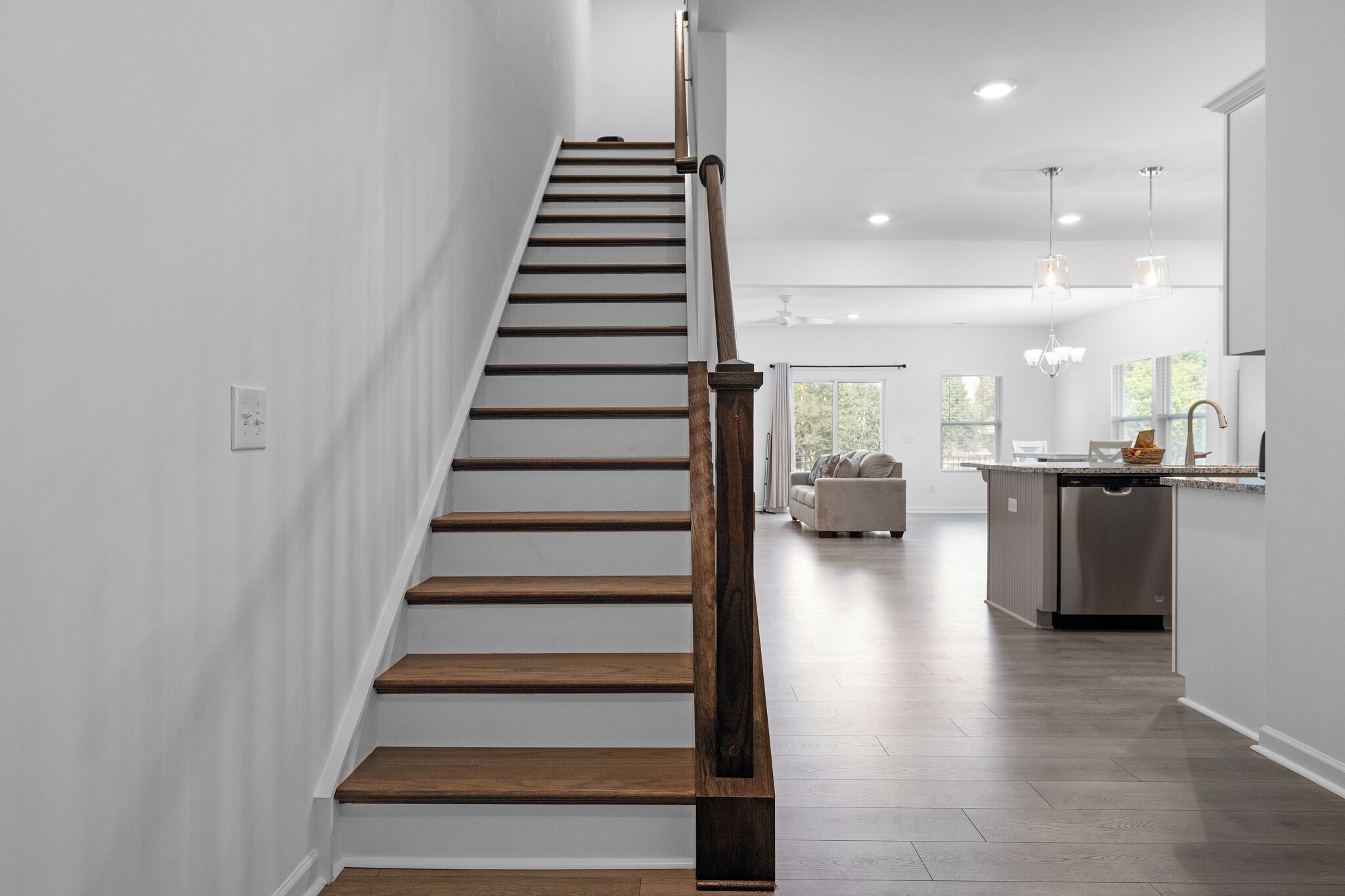 Un intérieur moderne avec un escalier en bois, un coin cuisine et un espace de vie doté d’un canapé.