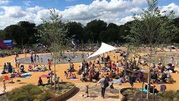 A public park with a sandy play area, benches, and trees.