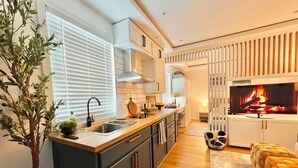 A modern kitchen with a central island, built-in cabinets, and a large window with blinds. - New Cozy Studio Apartment A (Tampa)