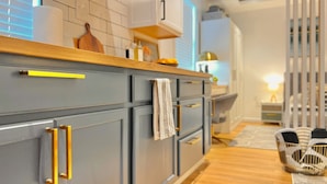 A modern kitchen with grey cabinets, wooden countertops, and a visible towel hanging on one of the doors. - New Cozy Studio Apartment A (Tampa)