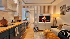 A modern kitchen with a central island, a dining area with a sofa and ottoman, and a living room with a fireplace. - New Cozy Studio Apartment A (Tampa)