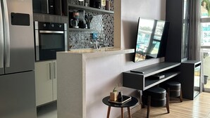 Een moderne keuken met roestvrijstalen apparatuur, een eethoek met een televisie, en uitzicht op de omgeving.
