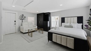 Ein modernes Schlafzimmer mit einem großen Bett, einer Couch, einem Couchtisch und einem Kleiderschrank.