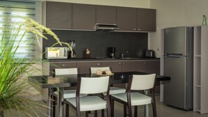 A modern kitchen with dark cabinets, a stainless steel refrigerator, a dining table with chairs, and a coffee maker. - Escape to Paradise 5-star VIP Resort, Private Beaches, Pools & Unlimited Dining (Puerto Plata)