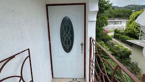 A white door with a decorative glass panel, a metal gate, and a tiled floor with a geometric pattern.