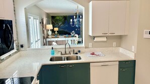 Una cocina moderna con estufa integrada, pileta doble y armarios verdes.