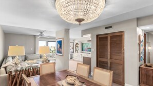 Ein Essbereich mit Holztisch, Stühlen, einer Chandelier und einer Couch mit Kissen.