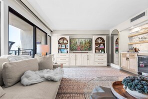 A modern living room with a sofa, a coffee table, a TV, and a fireplace. - 2-Story Penthouse - Gulf Views - Private Beach - Crib + Baby Gear - SILVER DUNES (Destin)