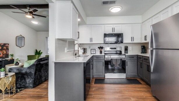 Una cocina moderna con armarios blancos, electrodomésticos de acero inoxidable y una isla central.