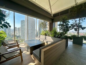 Un espace intérieur moderne doté d’un coin salon, de grandes fenêtres et de plantes d’intérieur.