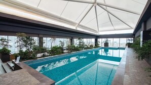 An indoor swimming pool with a glass ceiling, surrounded by plants and city views. - Studio/Loft Apartment in Vitant by BeGrand Anahuac, close to Polanco. (Ciudad de México)