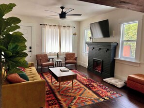 A living room with a sofa, chairs, a coffee table, a fireplace, and a TV mounted on the wall. - Minutes to Beach, Fire Pit, Love Pets, Huge Yard (Long Beach)