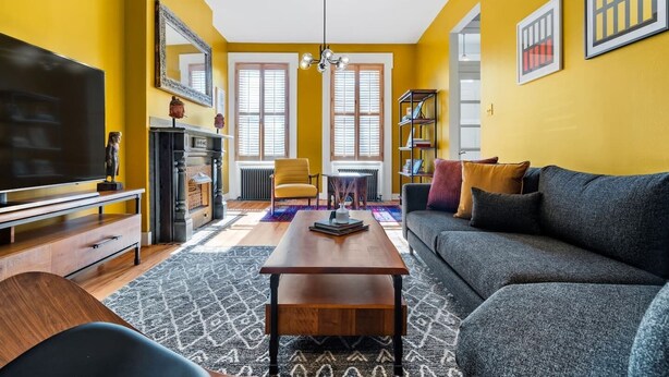 Un salon avec un canapé, un téléviseur, une cheminée et des étagères à livres.