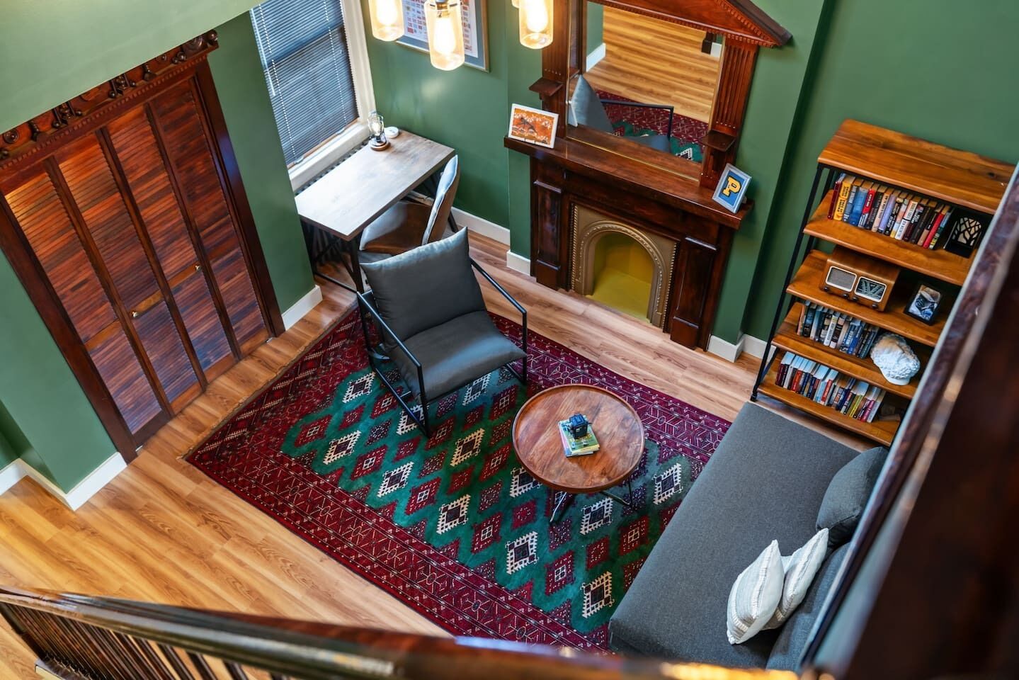 A cozy living room with a fireplace, a bookshelf, a dining table, and a patterned rug.