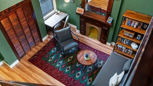 Un salon chaleureux avec une cheminée, une bibliothèque, une table à manger et un tapis à motifs.