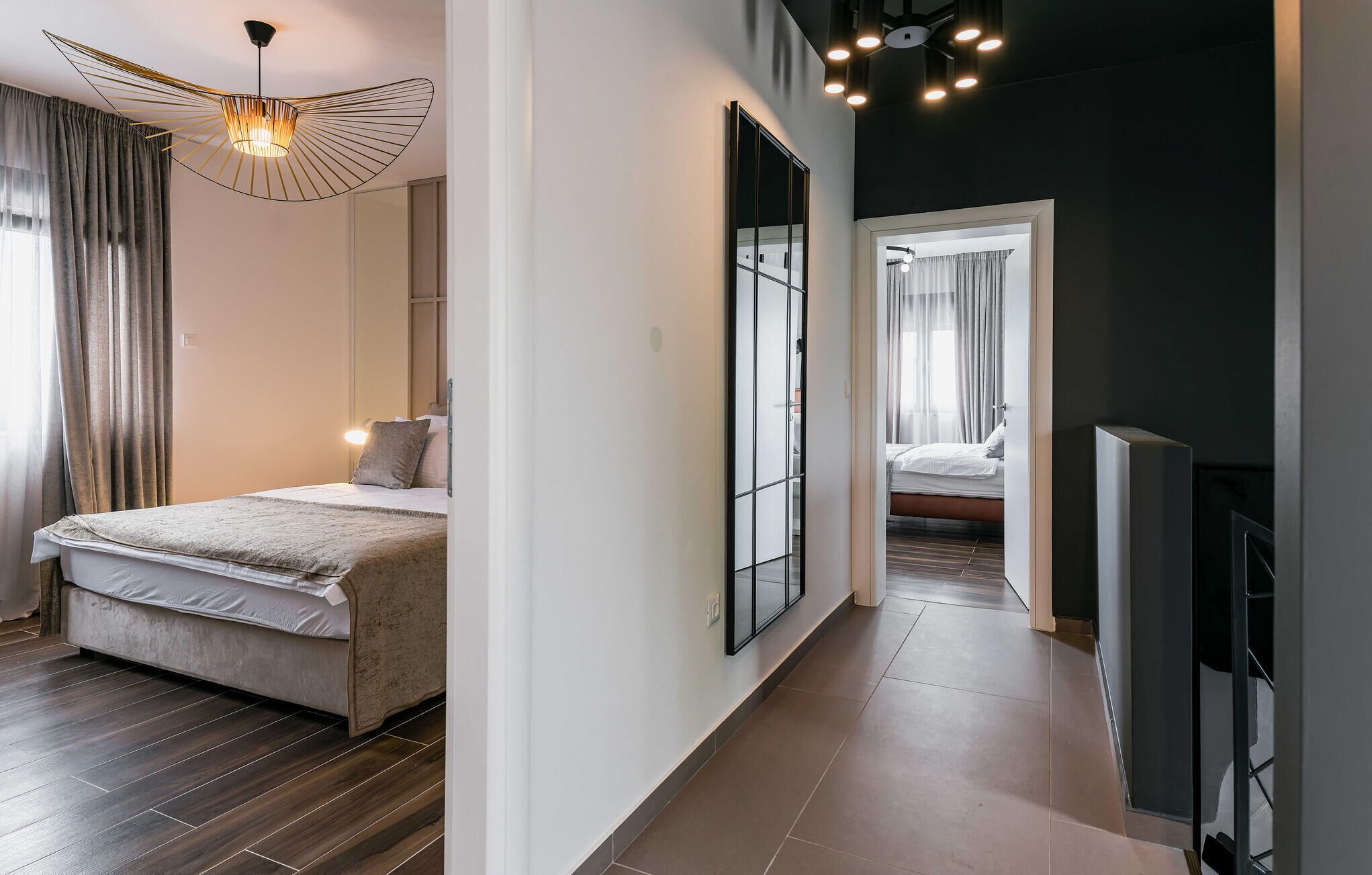 Een moderne slaapkamer met een groot bed, een bijzondere plafondlamp en uitzicht op een andere kamer.