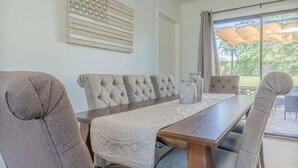 A dining area with a long wooden table, cushioned chairs, and a decorative wall piece. - Charter Oak's Retreat- Near Ft. Benning - Perfect for Graduations/Best Ranger (Columbus)