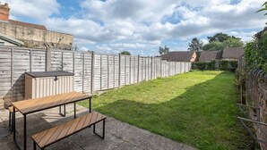 A backyard with a wooden fence, a picnic table, and a shed.