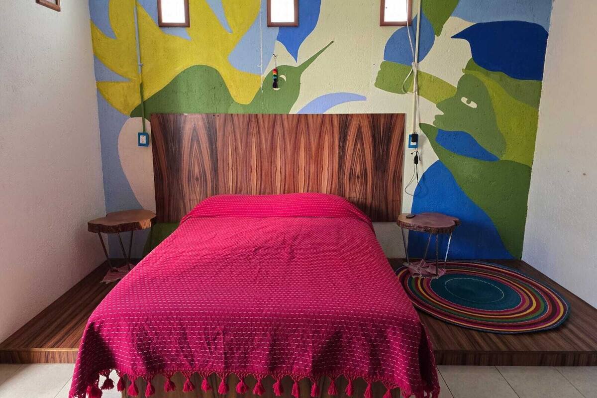 A room with a bed, a wooden headboard, and abstract wall art.