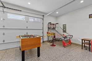 Une pièce équipée d’un baby-foot, d’un panier de basket et d’une petite table.