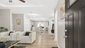 Un salon moderne avec un canapé blanc, une table basse et une porte sombre.