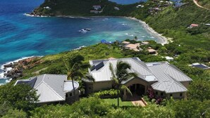 A coastal property with multiple buildings, a beach, and a small island in the background. - Introducing Blue View (Cruz Bay)