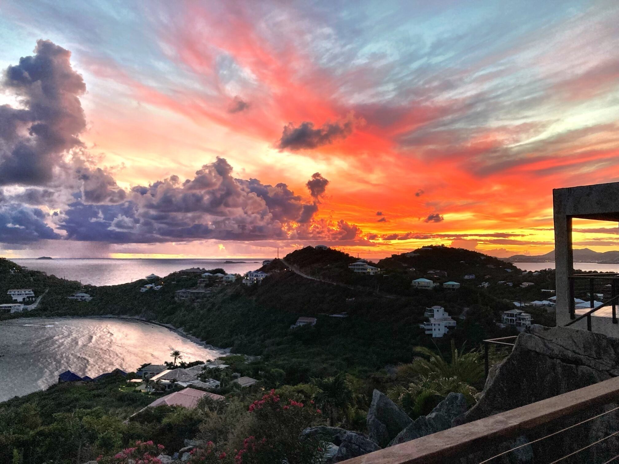 A coastal landscape with a sunset, houses, and a rocky terrain.