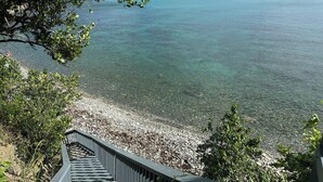 A staircase leading to a beach with clear water and a distant island. - Introducing Blue View (Cruz Bay)
