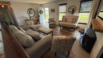 A spacious living room with a sofa set, patterned chairs, a fireplace, and a ceiling fan.