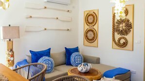 Un salon avec un canapé, des coussins bleus, une table basse en bois et des objets décoratifs fixés au mur.
