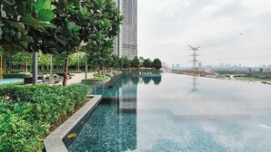 A modern residential area with a long swimming pool, surrounded by lush greenery and tall buildings in the background. - Ancestry 3BR @ M Vertica | MRT Access+Netflix+WiFi (Cheras)