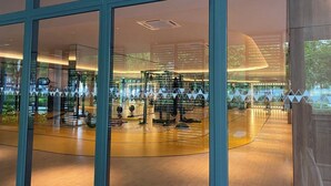 A modern interior with large glass windows, a central circular area with a display, and a wooden floor. - Ancestry 3BR @ M Vertica | MRT Access+Netflix+WiFi (Cheras)