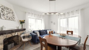 A dining area with a wooden table and chairs, a blue sofa, and a fireplace. - Lagoon View Villa - Ocean Serenity (Óbidos)
