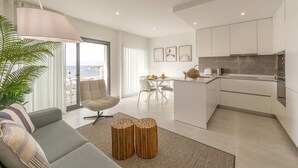 Un appartement moderne comprenant un salon, un coin repas et une cuisine. Une grande fenêtre offre une vue sur la ville.