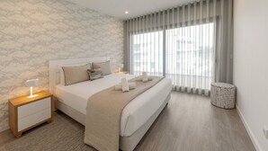 Une chambre moderne avec un grand lit, des tables de chevet, une commode, un mur à motifs et une fenêtre avec des rideaux.