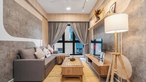 Una sala de estar moderna con un sofá gris, una mesa de centro de madera y un televisor sobre un mueble de madera.