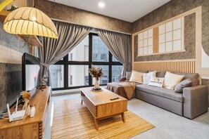 Un salon moderne avec un canapé, une table basse en bois et un téléviseur.