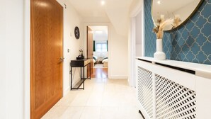 A hallway with a wooden door, a black console table, and a white radiator. - 3BR Group Stay Penthouse Near General Hospital (Southampton)