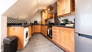 A modern kitchen with wooden cabinets, a built-in washing machine, and a stainless steel refrigerator. - 3BR Group Stay Penthouse Near General Hospital (Southampton)