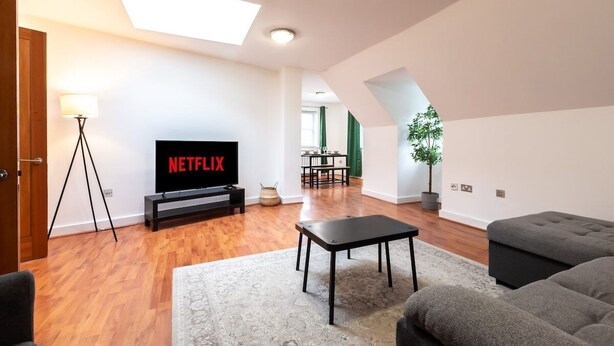A modern living room with a flat-screen TV, a sofa, a coffee table, and a lamp. - 3BR Group Stay Penthouse Near General Hospital (Southampton)