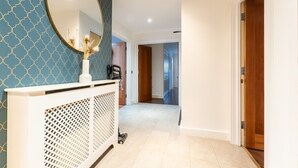 A hallway with a white console table, a round mirror, and a patterned wall. - 3BR Group Stay Penthouse Near General Hospital (Southampton)