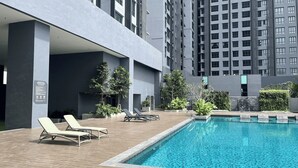Uma área moderna com piscina ao ar livre, espreguiçadeiras e vegetação exuberante ao redor.