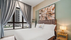 Quarto de hotel com uma cama grande, mesa de cabeceira com abajur, janela com cortinas e vista para a cidade.