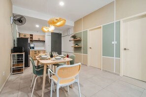 Une cuisine compacte comprenant un coin repas, un réfrigérateur, un four à micro-ondes et un ventilateur.