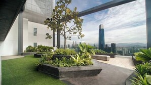 Ein moderner Dachgarten mit Kunstgrashalm, verschiedenen Pflanzen und Blick auf die Stadt.
