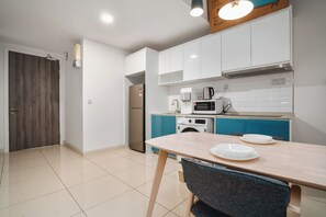 Una cocina moderna con armarios blancos, un refrigerador de acero inoxidable, un microondas y una cafetera.
