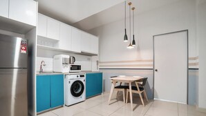 Eine moderne Küche mit Edelstahlkühlschrank, Waschmaschine, Mikrowelle und einem Esstisch mit Stühlen.