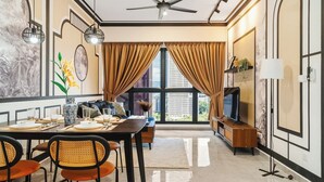 Ein moderner Essbereich mit Tisch für vier Personen, einer Couch, einem Fernseher und einem Deckenventilator.