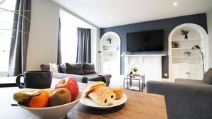 A modern living room with a dining table, a bowl of fruit, and a plate of pastries. - Regent Parade Retreat, sleeps 6, Free parking, (North Yorkshire)