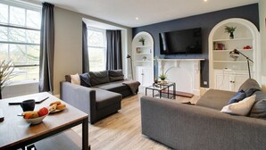 A modern living room with a grey sofa, a coffee table, and a TV mounted on the wall. - Regent Parade Retreat, sleeps 6, Free parking, (North Yorkshire)